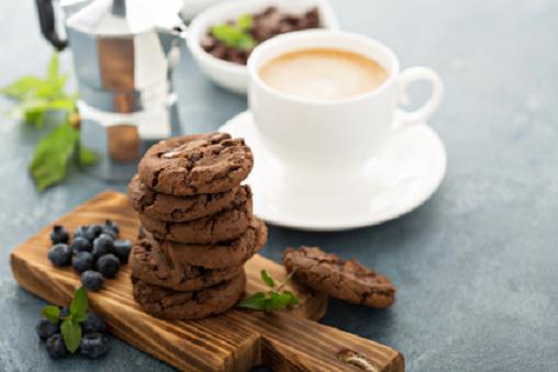 Double chocolate cookies with chips stacked on a board served with coffee